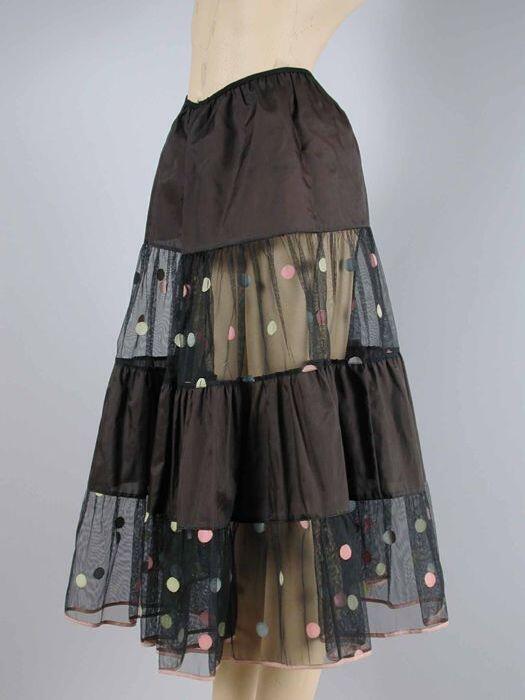 Zwarte nylonpetticoat, stroken om en om gladde zwarte stof en stug zwart gaas met lichtgele, roze…