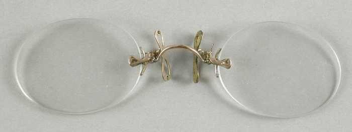 Knijpbril of pince-nez, ovale glazen op sterkte zonder montuur, kleine goudkleurige metalen brug…