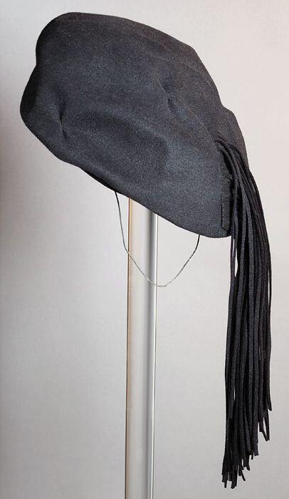 Ronde zwart vilten baret, met achter afhangende viltslierten