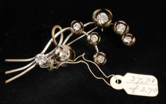 Broche, zilverkleurig metaal met bloemvormpjes met kunstdiamantjes, kapper Van Vliet