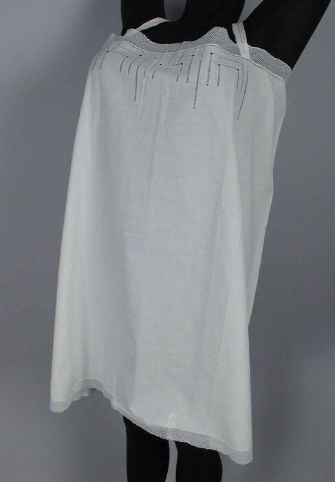 Wit katoenen wijd hemdje (chemise enveloppe) met schouderbandjes, versierd met ajour en kant in…