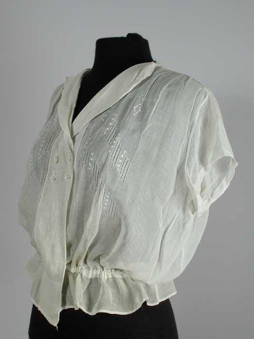 Blouse met korte mouw van transparant crèmekleurig katoen met opennaaiwerk, koordje in de taille