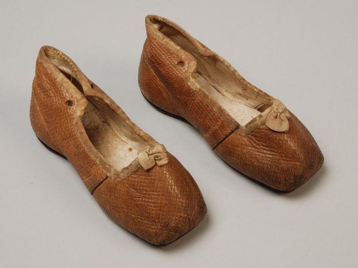 Babyschoenen van beige leer, laag model met rechte neus, randen met lint omboord, vetersluiting