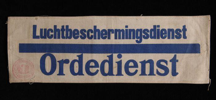Mouwband, wit keperkatoen met opdruk in donkerblauw, "Luchtbeschermingsdienst Ordedienst", rode…