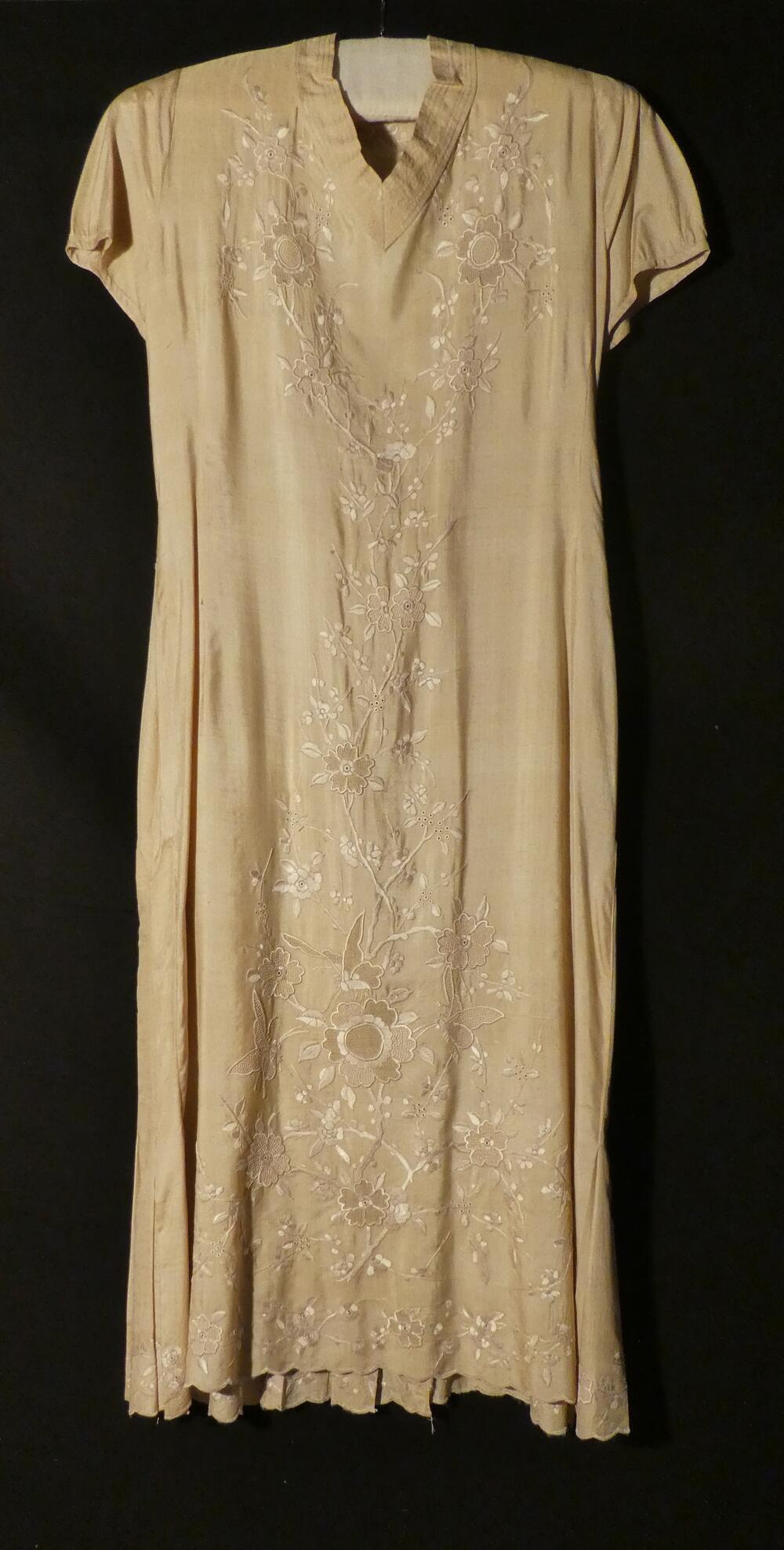 Jurk van beige shantung zijde in lang model met V-hals en korte ingezette mouw. Met middenvoor,…