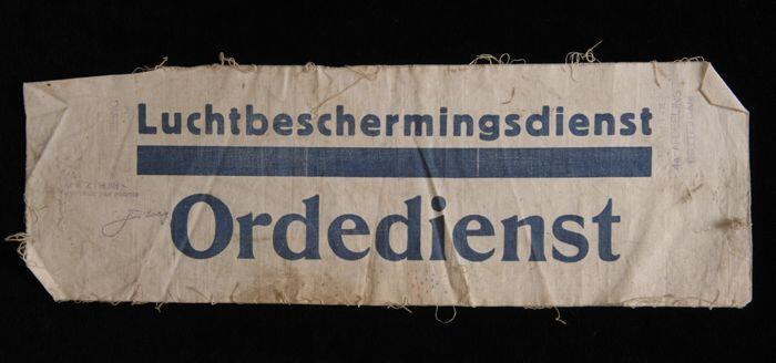 Onafgewerkte mouwband, wit katoen met opdruk in donkerblauw, "Luchtbeschermingsdienst Ordedienst"…