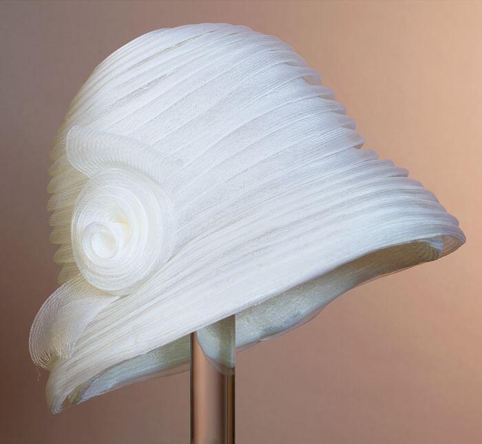 Ronde cloche, geheel van wit crin-band, gevouwen en spiraalvormig aan elkaar genaaid, garnering van…