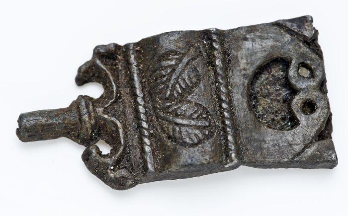 Fragment tinen beslag, riemtong, gegraveerde bladeren als versiering