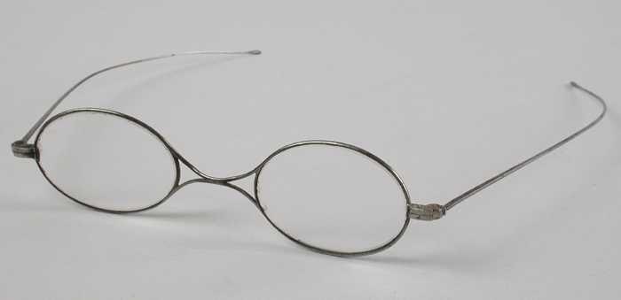 Bril met ovale glazen op sterkte, zilverkleurig metalen montuur met X-vormige brug en smalle…