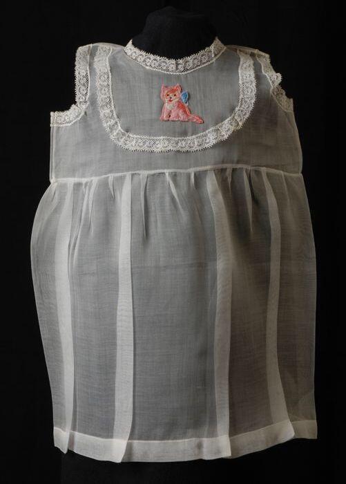 Babyjurk, mouwloos schortmodel van transparant wit nylonmet wit kant en geborduurd poesje, 'Femifra…