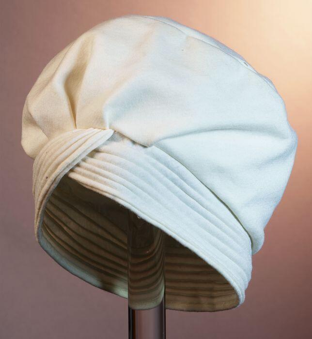 Baret van crèmekleurig tricot met geribbelde rand rond entree