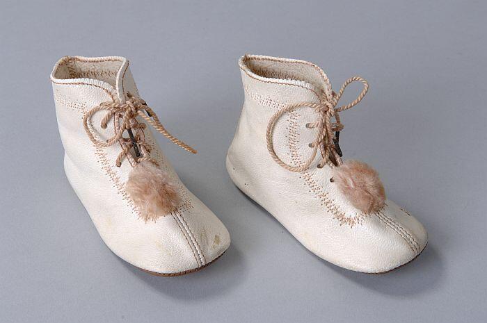 Roomwitte leren babyschoentjes met zalmkleurige veters, stiksels en wollen pompoentjes