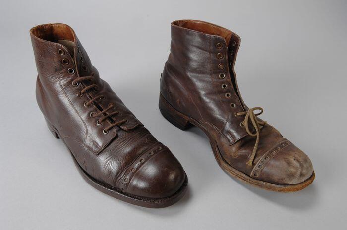 Paar herenschoenen van bruin leer, één schoen versleten, andere schoen gerepareerd,…