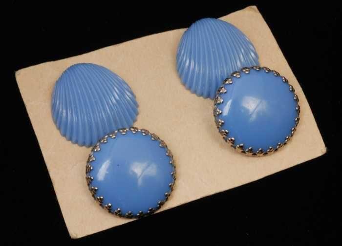 Twee verschillende paren oorbellen, beiden clips met lichtblauwe plastic knop, op karton, kapper…