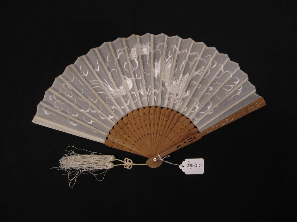 Vouwwaaier, montuur van bewerkt sandelhout, blad van wit gaas of organza met voorstelling van draak…