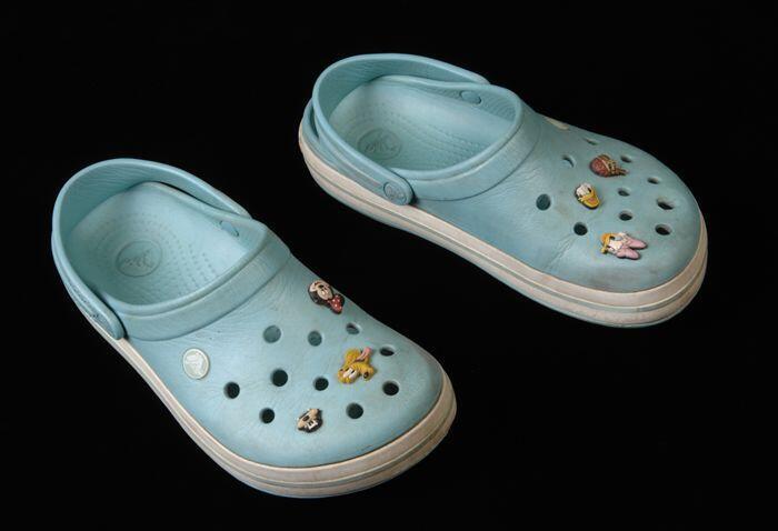 Paar lichtblauwe crocs, maat "7", in de ventilatiegaatjes gedecoreerd met Disneyfiguren en…