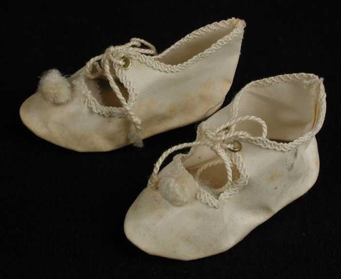 Paar miniatuur platte schoenen van wit linnen(?) met open wreef, vetersluiting en wit pompoentje,…
