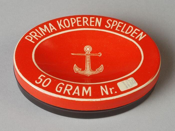 Ovaal rood, wit en zwart blik, "Prima koperen spelden"