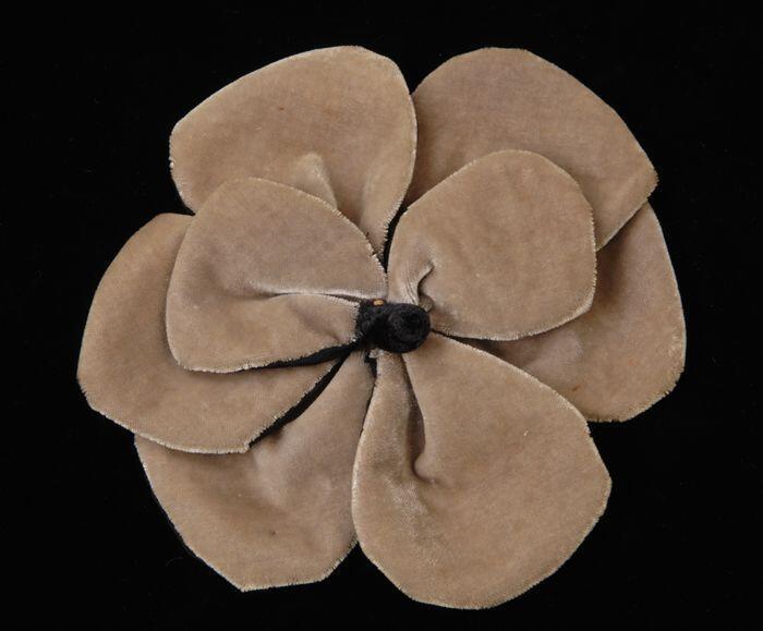 Corsage, bloemvorm met zes onderbladeren en twee kleinere boven van beige velours aan de bovenzijde…