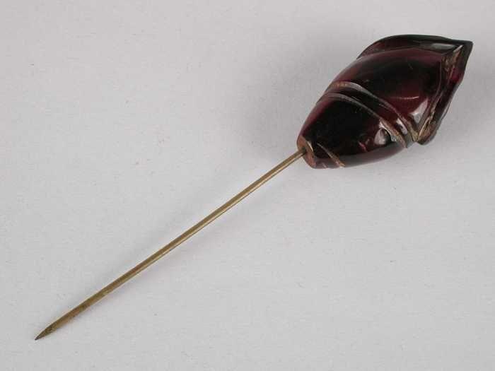 Hoedenspeld van roodbruin kunststofop een korte koperkleurige pin