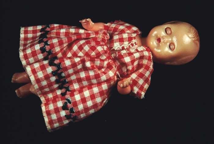Kleine pop, Witte baby van roze kunststof met slaapogen en draaibare ledematen in wit katoenen…