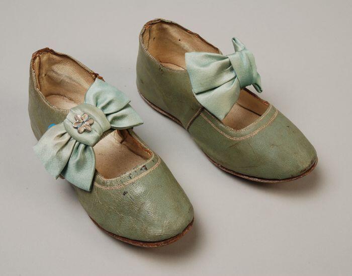 Mintgroene leren kinderschoenen met wreefbandjes waarop een satijnen strik met sierknoopje, bandje…