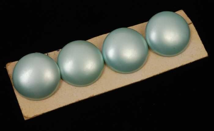 Twee paar oorbellen, clip met ronde mintgroene plastic knop met paarlemoerglans, op karton, kapper…