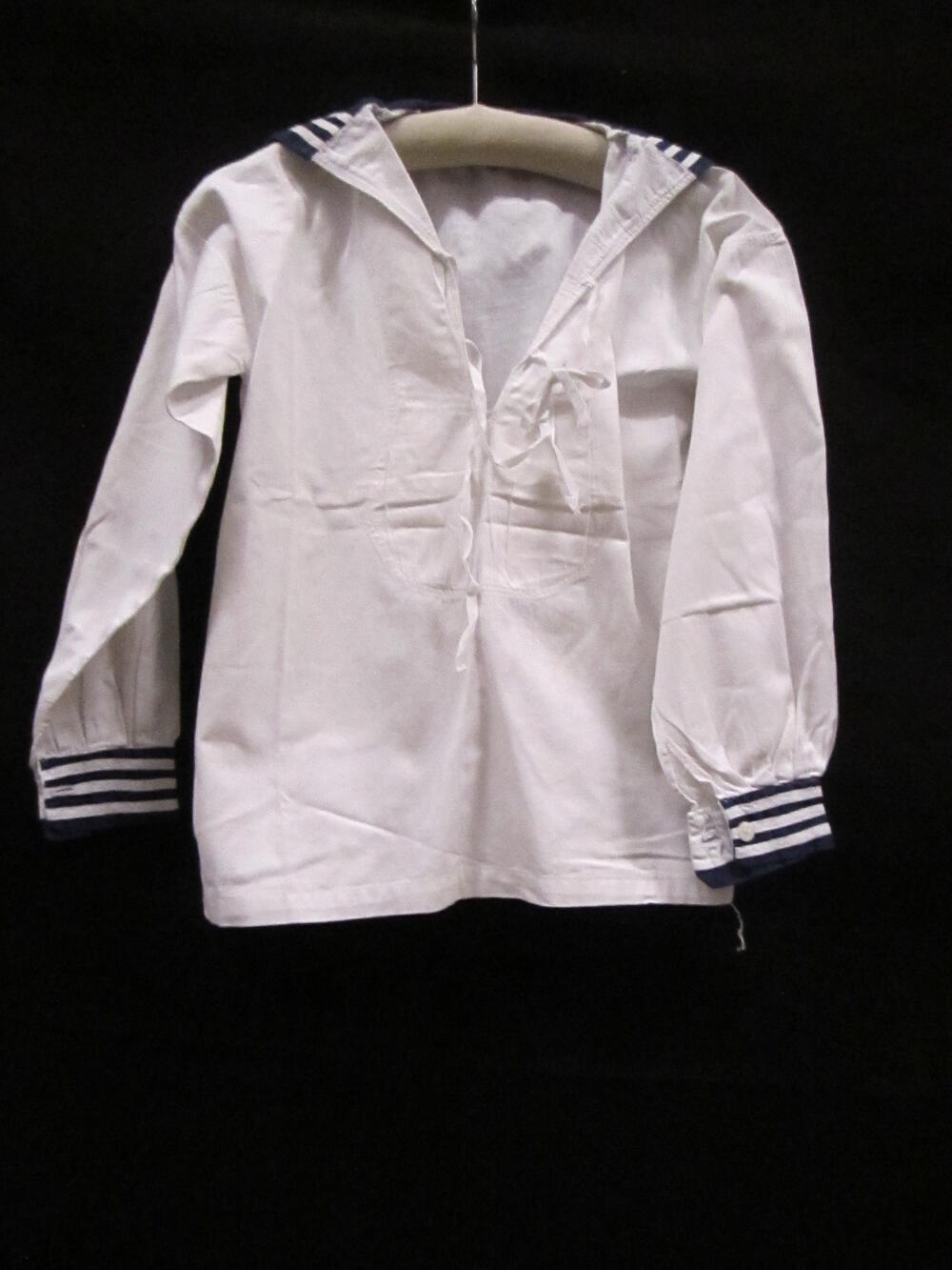 Blouse (jongen) van wit katoen, behorende tot matrozenpak. Recht model met lange mouwen,…