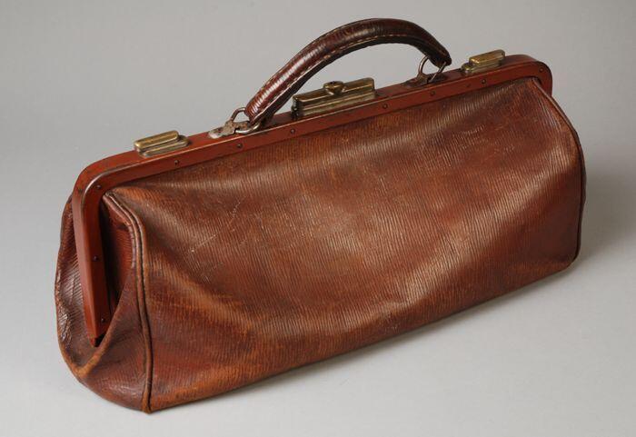 Handtas van bruin leer, lang smal model met brede beugelsluiting over de lengte van de tas en één…