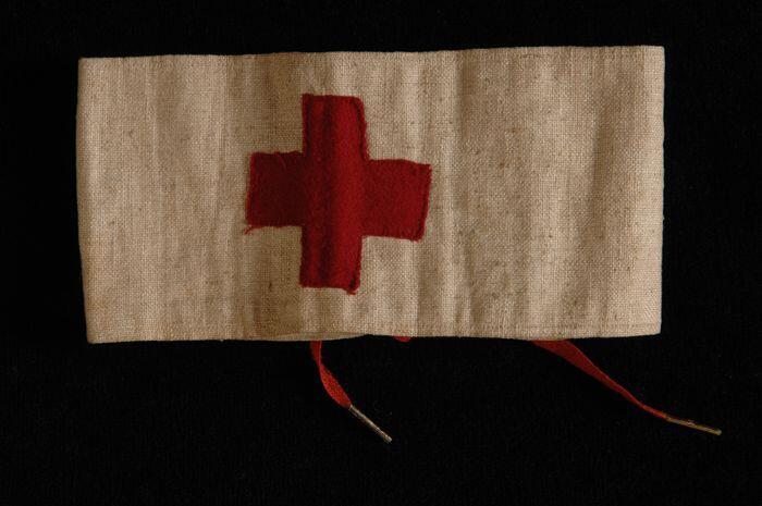 Mouwband van wit linnen met geappliqueerd rood kruis, rijgsluiting met rode veter, "J.B. Crol"