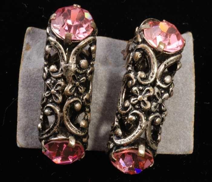 Eén paar oorbellen, clip met kokervormige metalen huls met florale motieven en twee roze…