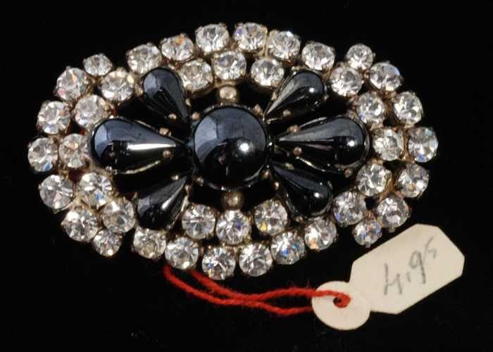 Ovale broche met veel kunstdiamantjes in een zilverkleurige vattin rondom druppelvormige glanzende…