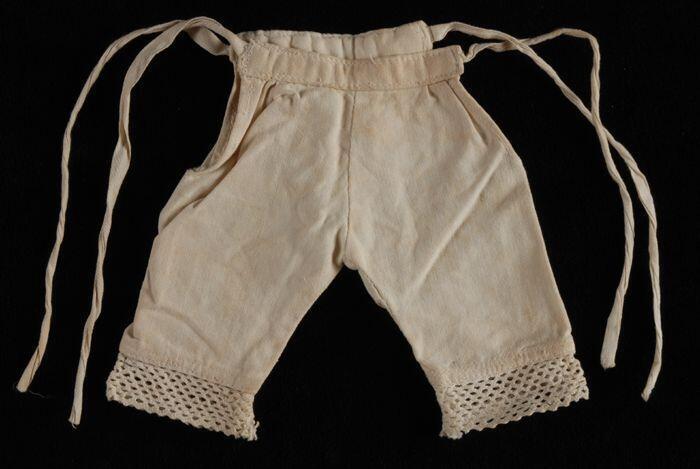 Lange poppenonderbroek van wit katoen met kant langs de pijpen, naaioefening