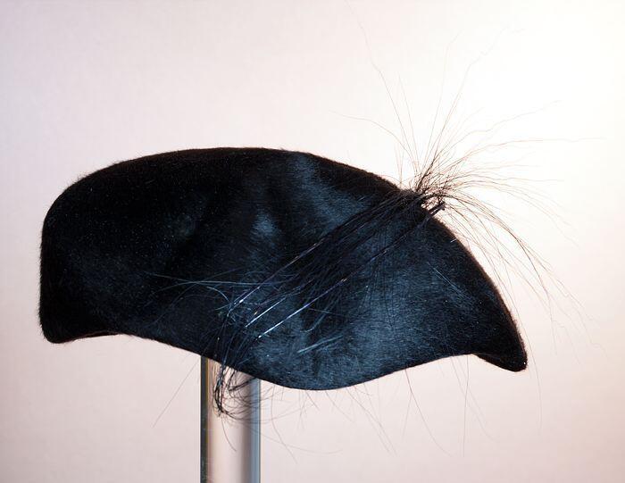 Ronde baret, zwart vilt met vijf lange zwarte veren schuin over het oppervlak