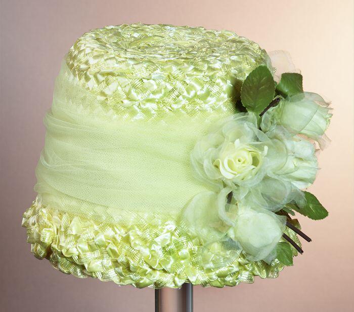 Cloche van geel imitatiestro en raffiagegarneerd met geel tule en gele kunstrozen