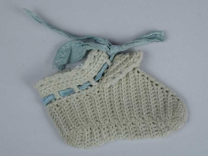Paar babysokken gehaakt van lichtblauwe wol blauw zijdelint door de enkel geregen
