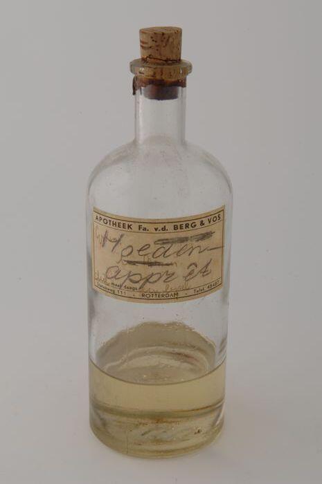 Glazen flesje met kurk, gevuld met hoedenapprêt, met apothekersetiket "APOTHEEK Fa. V.D. BERG & VOS…