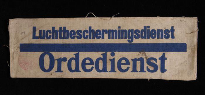 Mouwband, wit keperkatoen met opdruk in donkerblauw, "Luchtbeschermingsdienst Ordedienst", rode…