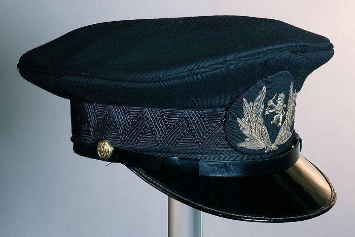 Uniformpet van zwart keper met zwarte klep, goudgeborduurd embleem, uniform Havendienst Rotterdam