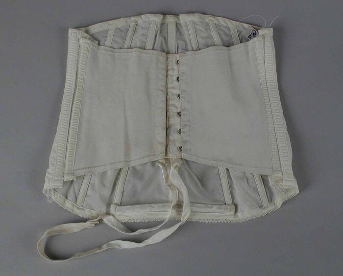 Witte nylonkorset, kant langs bovenrand, twee verticale stroken met geborduurd bloemmotief,…
