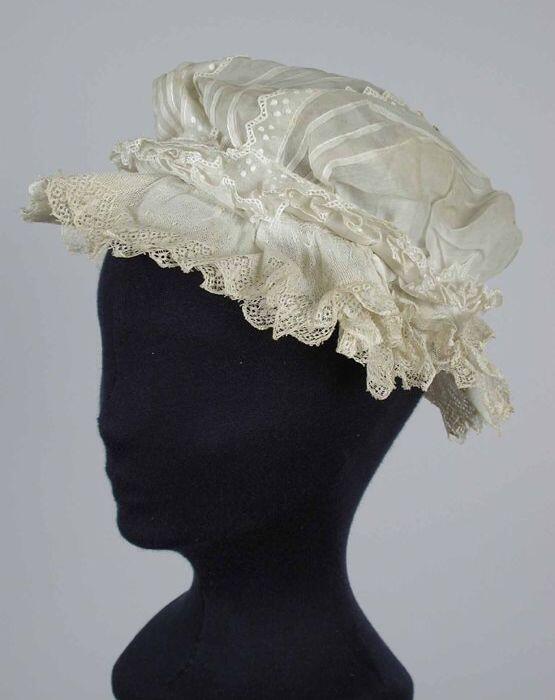 Boudoirmuts van wit glasatist, banen oprijgjes en getand broderie over de bol, brede kantruche…