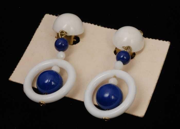Paar oorbellen, clip met hanger van wit plastic, witte ring met blauwe en witte kralen, op wit…