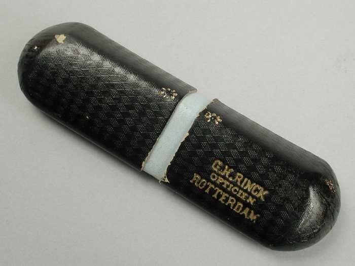 Brillenkoker van zwart karton, twee in elkaar schuivende delen, "G.H. Rinck Opticien Rotterdam"