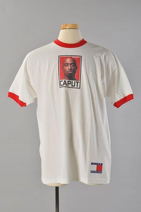 Wit t-shirt met rode boorden, kleurenfoto van zwarte man, opschrift "CAPUT", sticker met imitatie…