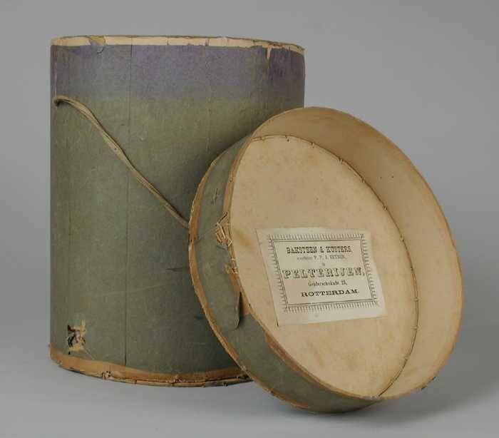 Cilindrische doos van karton bekleed met grijs papier met draaglint