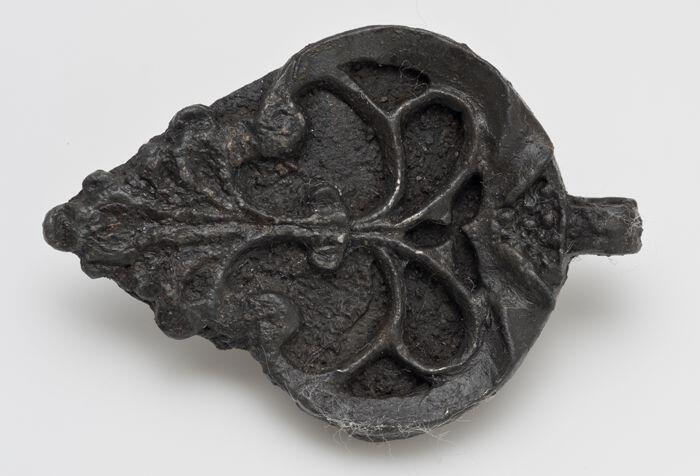 Hartvormige hanger of beslag met florale versiering in reliëf, met oog