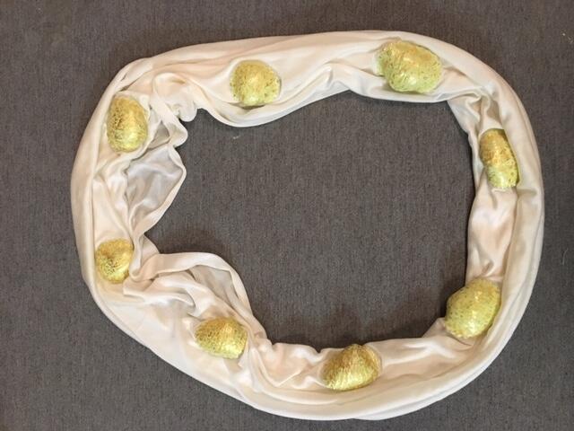 Halsdoek of halssnoer met schelpen. Lusvorm van witte zijden tricot, plaatselijk in 7 schelpvormige…