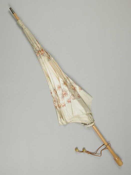 Lichte parasol, bekleding met bloemmotief, houten steel, koperen ring boven handvat en leren koord…