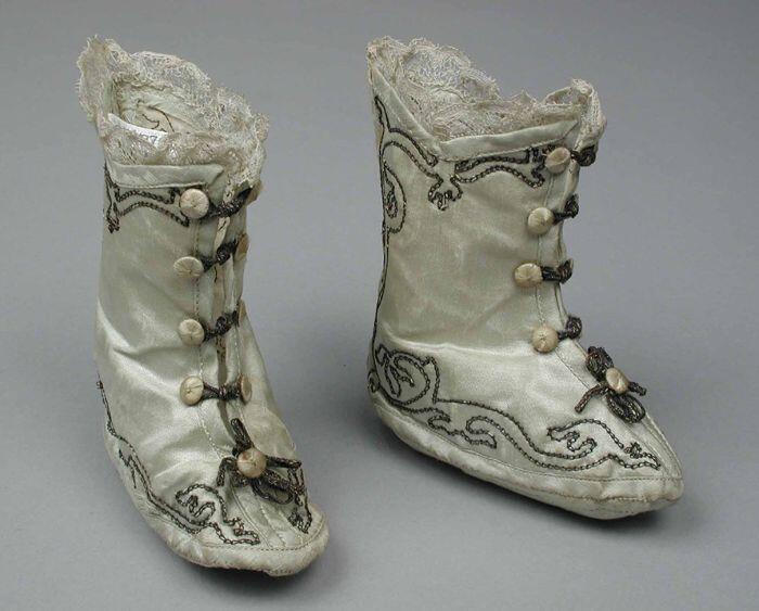 Babyschoenen, hoog model, zilverroen zijdesatijn met knoopsluiting en goudborduursel, rozet voorop…