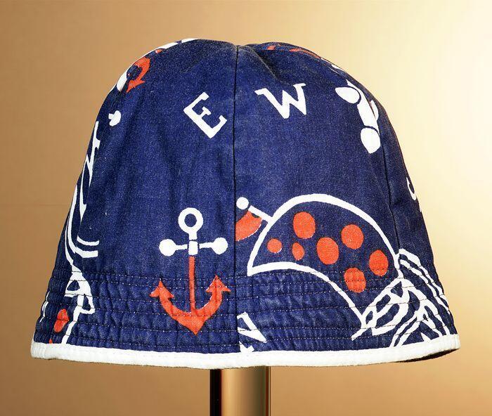 Zonnehoed van donkerblauw katoen met dessin in wit en rood met marine thema, doorgestikte rand met…